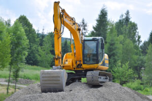 Excavator on a gravel mound in a green landscape, representing training for excavator ticket in Brisbane's mining industry.