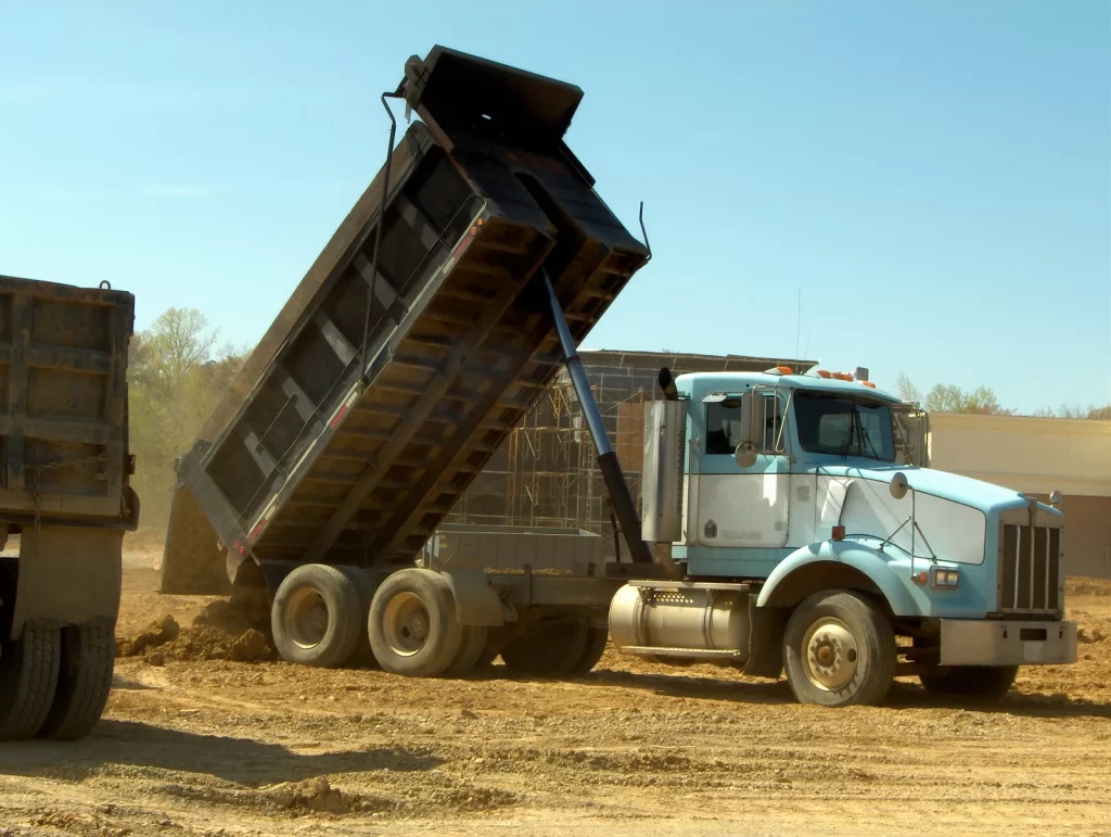 Dump truck unloading dirt on a construction site, representing training for a dump truck licence in Queensland.